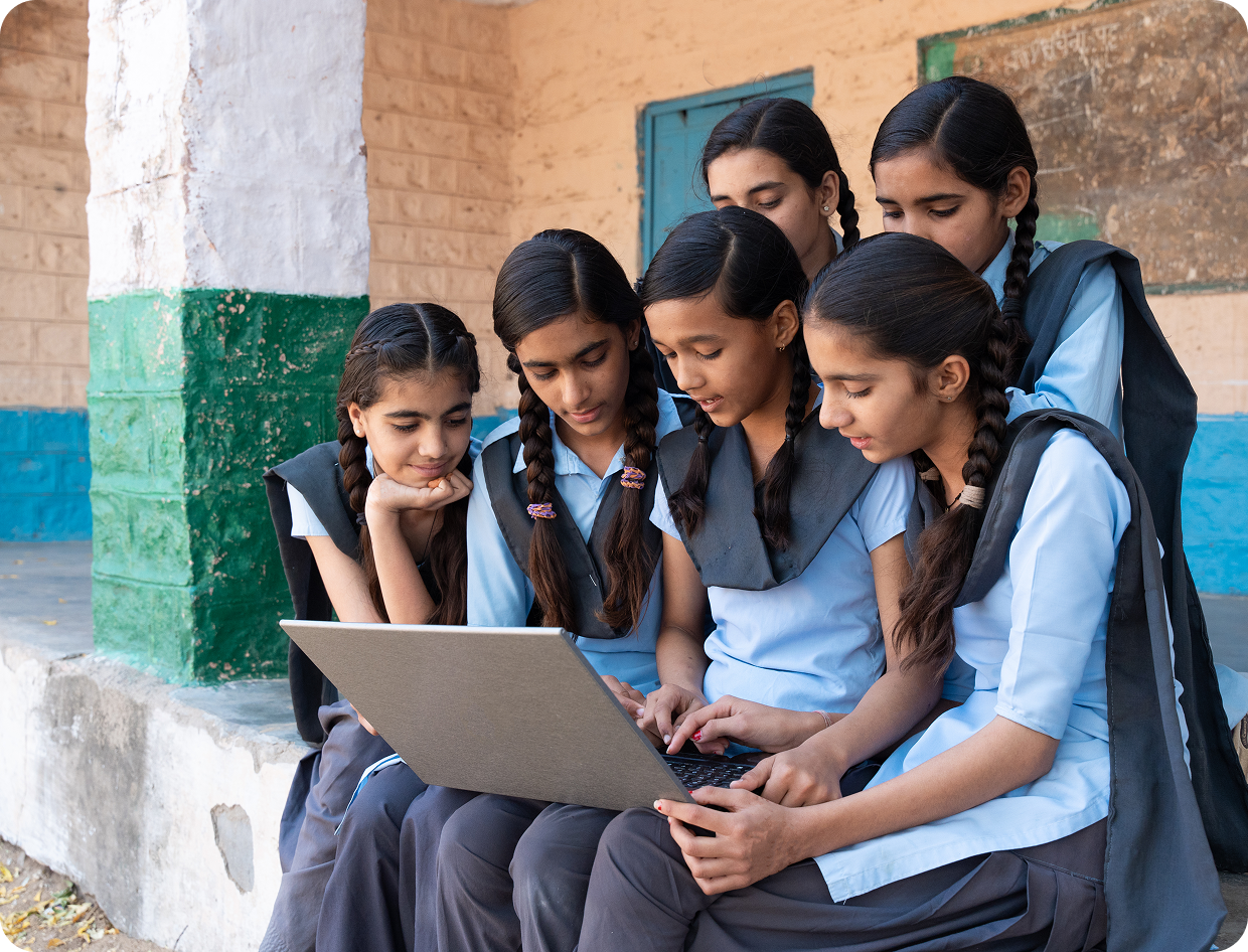 Girls in uniforms using a laptop together.