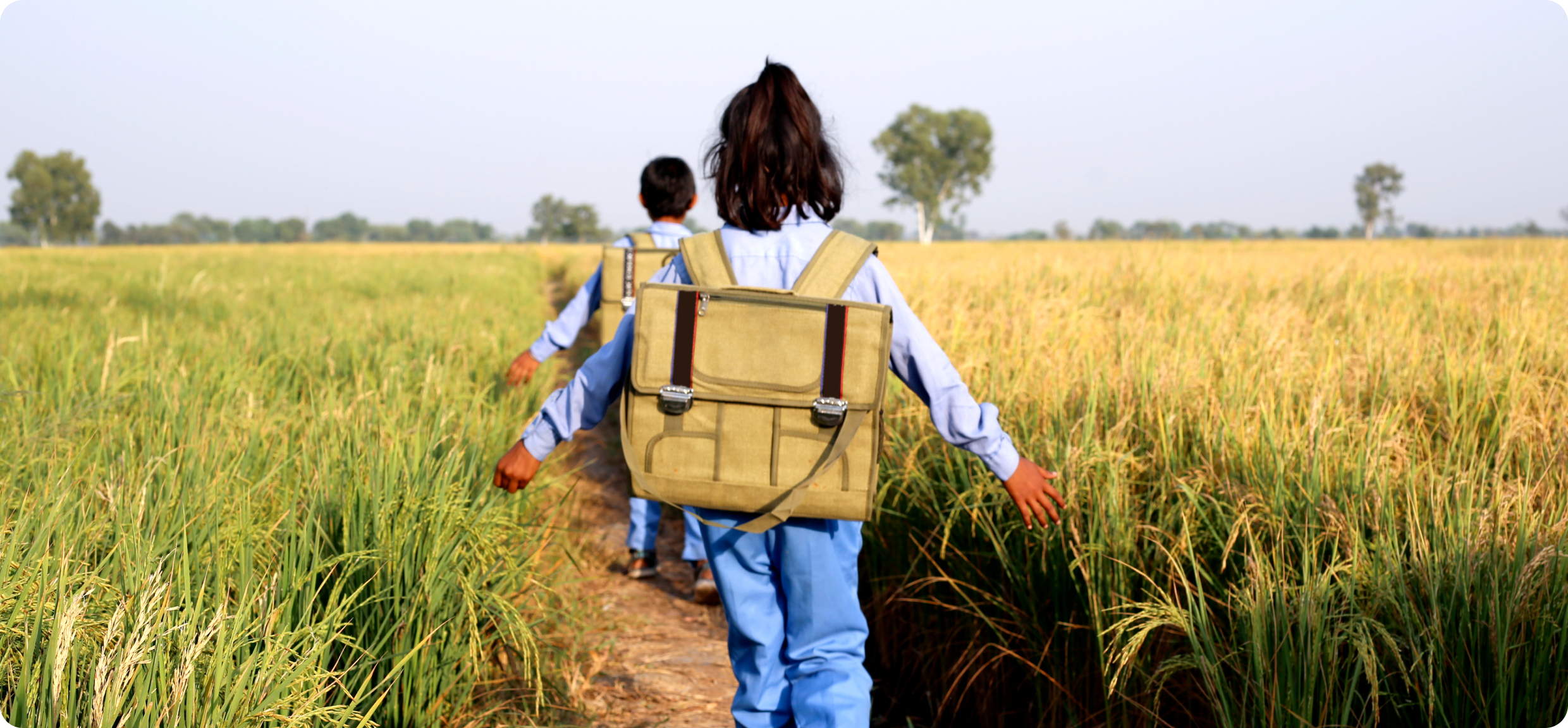 Children walking through a field to school.